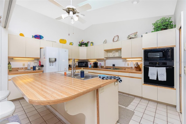 kitchen featuring high vaulted ceiling, light countertops, a sink, light tile patterned floors, and black appliances