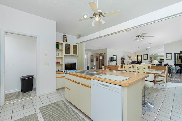 kitchen featuring a sink, dishwasher, open floor plan, a ceiling fan, and light tile patterned floors