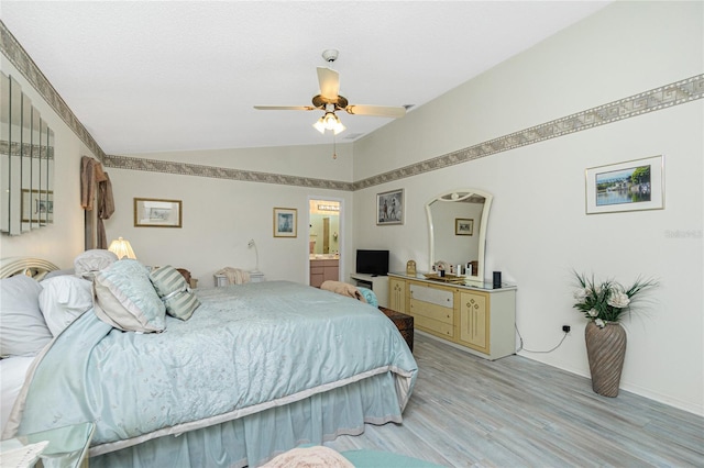 bedroom featuring ensuite bath, light wood-style floors, arched walkways, baseboards, and vaulted ceiling