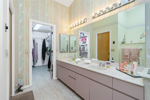 bathroom featuring a sink, tile patterned floors, wallpapered walls, and a spacious closet