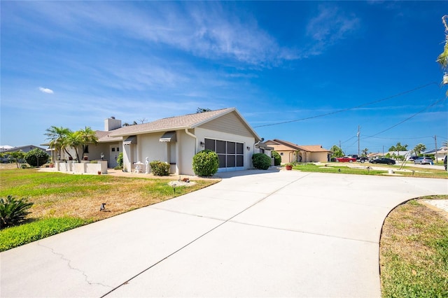 ranch-style home with stucco siding, a front yard, a chimney, and concrete driveway