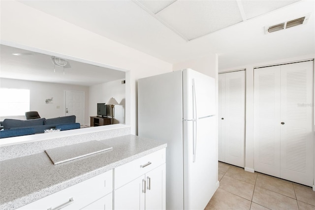 1531 Placida Rd Unit 4-103, Englewood, FL 34223 - kitchen featuring freestanding refrigerator, light tile patterned flooring, white cabinets, open floor plan, and light stone counters