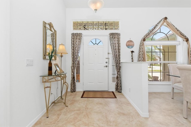 foyer featuring a healthy amount of sunlight, baseboards, and light tile patterned floors