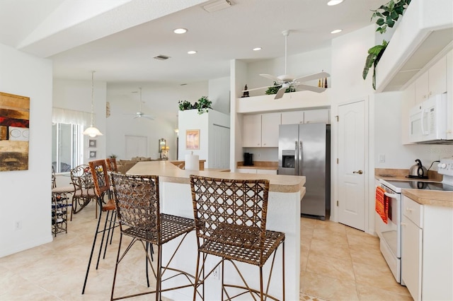 kitchen with visible vents, a breakfast bar, white appliances, high vaulted ceiling, and a ceiling fan