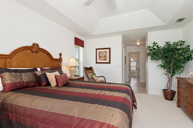 bedroom with multiple windows, a ceiling fan, a tray ceiling, and visible vents
