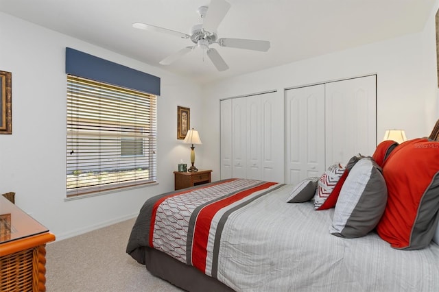 carpeted bedroom with baseboards, multiple closets, and ceiling fan