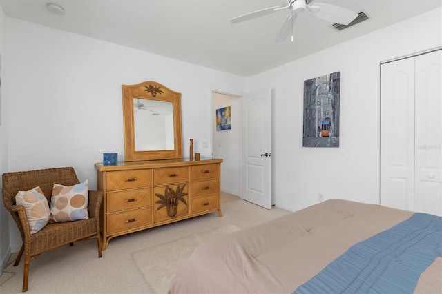 bedroom featuring visible vents, a ceiling fan, a closet, and light colored carpet