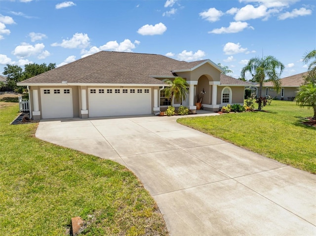 view of front of house featuring a front yard, roof with shingles, stucco siding, an attached garage, and driveway