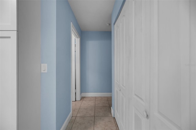 hall featuring light tile patterned flooring and baseboards