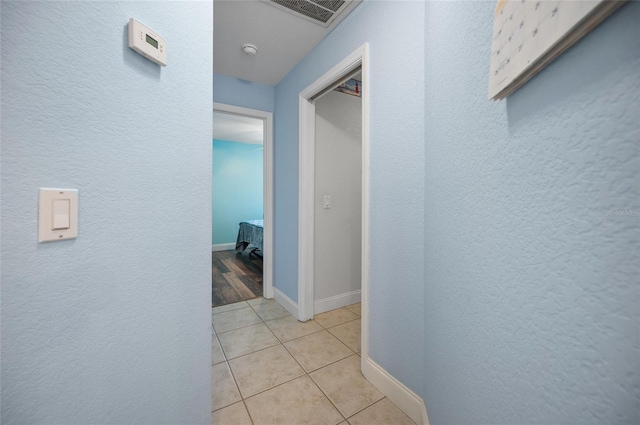 corridor featuring visible vents, baseboards, and a textured wall
