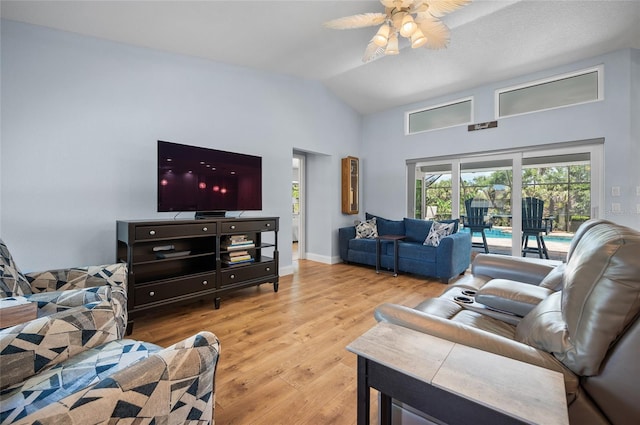 living area with a ceiling fan, wood finished floors, lofted ceiling, and a healthy amount of sunlight