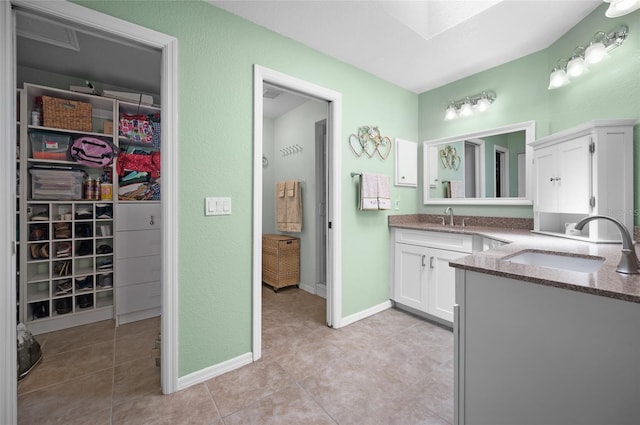 bathroom featuring vanity, a spacious closet, baseboards, and tile patterned floors