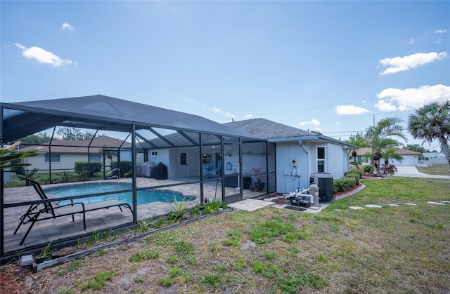 rear view of house with glass enclosure, an outdoor pool, a patio, stucco siding, and a lawn