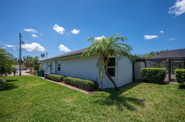view of property exterior featuring stucco siding, a lanai, and a lawn