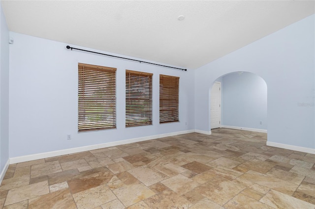 1155 Osceola Blvd, Englewood, FL 34223 - unfurnished room featuring baseboards, lofted ceiling, arched walkways, and stone tile floors