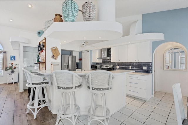 11 Amberjack Ln, Placida, FL 33946 - kitchen with light countertops, wall chimney exhaust hood, stainless steel appliances, white cabinetry, and a kitchen bar