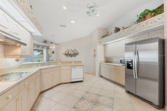 kitchen featuring light countertops, a peninsula, wallpapered walls, and appliances with stainless steel finishes