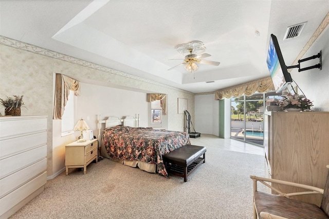 bedroom featuring a ceiling fan, visible vents, access to exterior, a raised ceiling, and light carpet