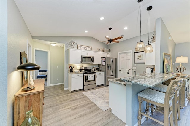 9211 Koma St, Port Charlotte, FL 33981 - kitchen with stainless steel appliances, vaulted ceiling, ceiling fan, light wood finished floors, and white cabinetry