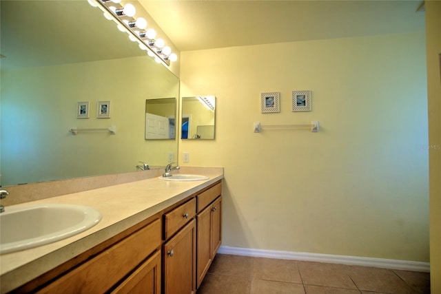 bathroom with a sink, double vanity, baseboards, and tile patterned floors
