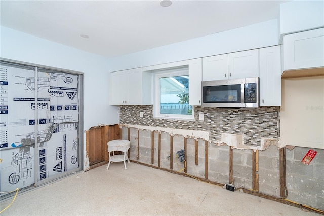 4093 Pelican Shores Cir, Englewood, FL 34223 - kitchen featuring stainless steel microwave, white cabinetry, and decorative backsplash
