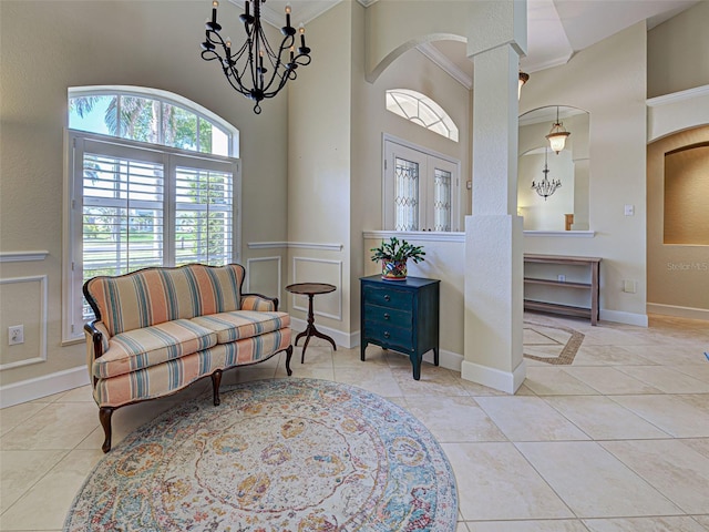 237 Rotonda Blvd E, Rotonda West, FL 33947 - living area featuring tile patterned flooring, a high ceiling, a chandelier, ornamental molding, and decorative columns