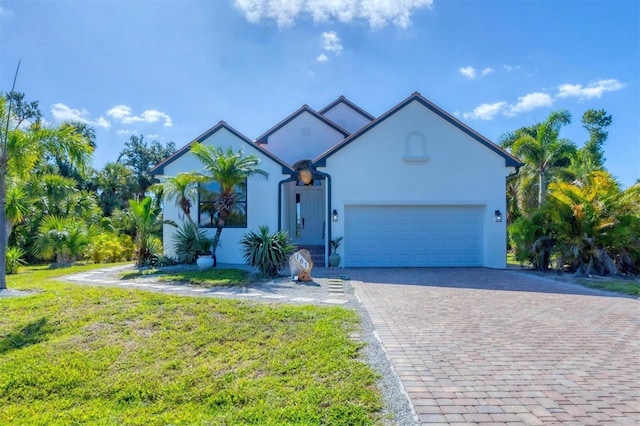 view of front facade featuring decorative driveway, an attached garage, stucco siding, and a front lawn