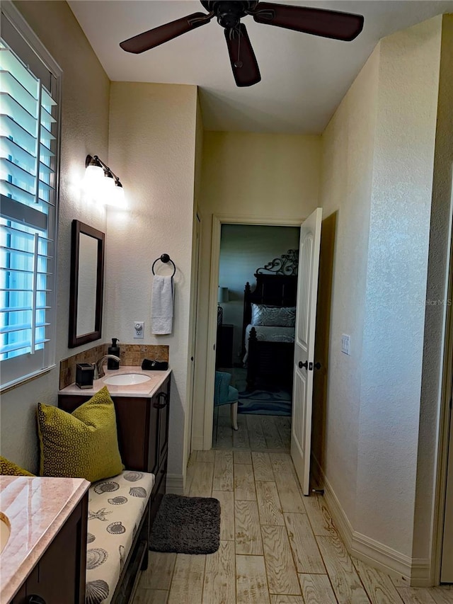 174 Broadmoor Ln, Rotonda West, FL 33947 - bathroom featuring ceiling fan, two vanities, wood finished floors, connected bathroom, and a textured wall