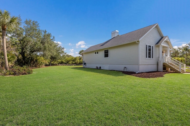 9144 Spring Valley Rd, Englewood, FL 34224 - back of property with a lawn, a chimney, stairway, and roof with shingles