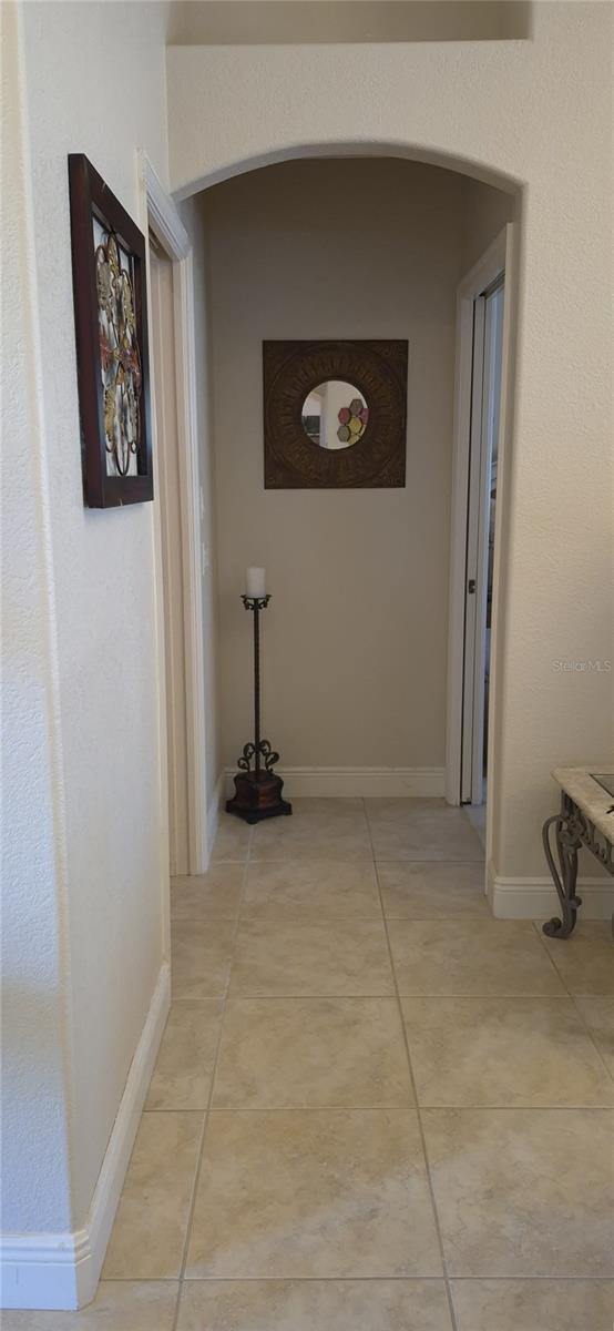 19 Medalist Way, Rotonda West, FL 33947 - hallway with arched walkways, light tile patterned flooring, and baseboards