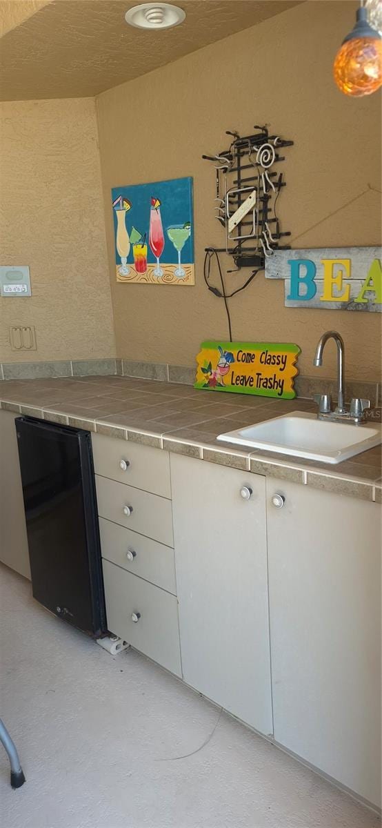 19 Medalist Way, Rotonda West, FL 33947 - kitchen featuring a sink, white cabinetry, light countertops, and a textured wall