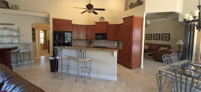 19 Medalist Way, Rotonda West, FL 33947 - kitchen with a towering ceiling, arched walkways, black appliances, light tile patterned flooring, and a ceiling fan