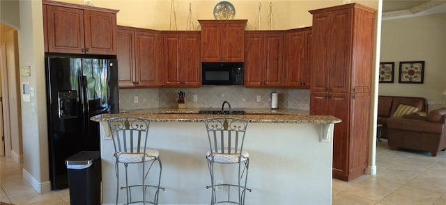 19 Medalist Way, Rotonda West, FL 33947 - kitchen with black appliances, light tile patterned floors, light stone counters, decorative backsplash, and a center island