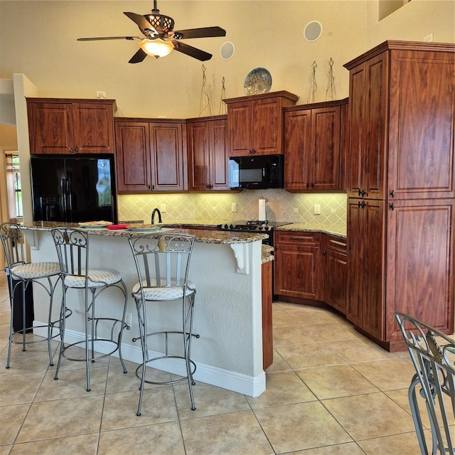 19 Medalist Way, Rotonda West, FL 33947 - kitchen with black appliances, ceiling fan, tasteful backsplash, a kitchen breakfast bar, and stone countertops