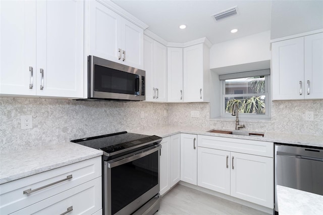 2700 N Beach Rd Unit A201, Englewood, FL 34223 - kitchen featuring stainless steel appliances, a sink, white cabinets, light stone counters, and decorative backsplash