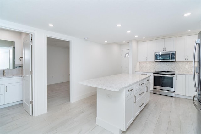 2700 N Beach Rd Unit A201, Englewood, FL 34223 - kitchen with stainless steel appliances, decorative backsplash, white cabinets, a center island, and recessed lighting