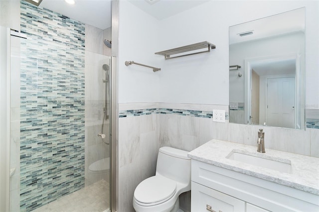 2700 N Beach Rd Unit A201, Englewood, FL 34223 - bathroom with a stall shower, tile walls, toilet, vanity, and a wainscoted wall