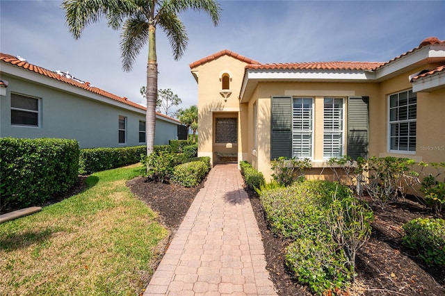 142 Savona Way N, Venice, FL 34275 - property entrance with a tiled roof, stucco siding, and a yard