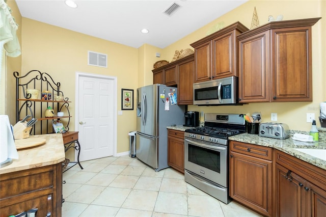 142 Savona Way N, Venice, FL 34275 - kitchen with appliances with stainless steel finishes, brown cabinets, light stone counters, and recessed lighting