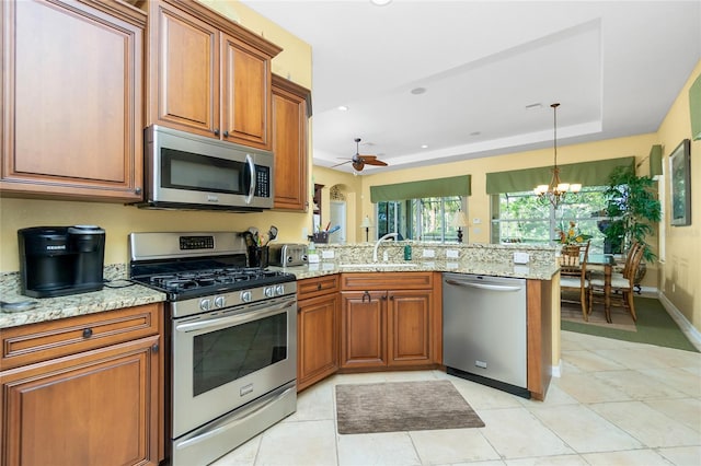 142 Savona Way N, Venice, FL 34275 - kitchen with appliances with stainless steel finishes, a sink, a peninsula, brown cabinets, and recessed lighting