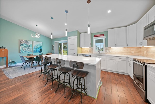 171 Mark Twain Ln, Rotonda West, FL 33947 - kitchen with stainless steel appliances, a sink, a kitchen bar, hardwood / wood-style flooring, and tasteful backsplash