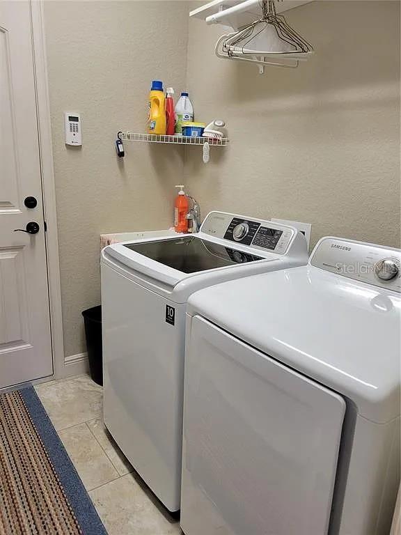 142 Yellow Pine Dr, Rotonda West, FL 33947 - laundry area featuring washing machine and clothes dryer and light tile patterned floors