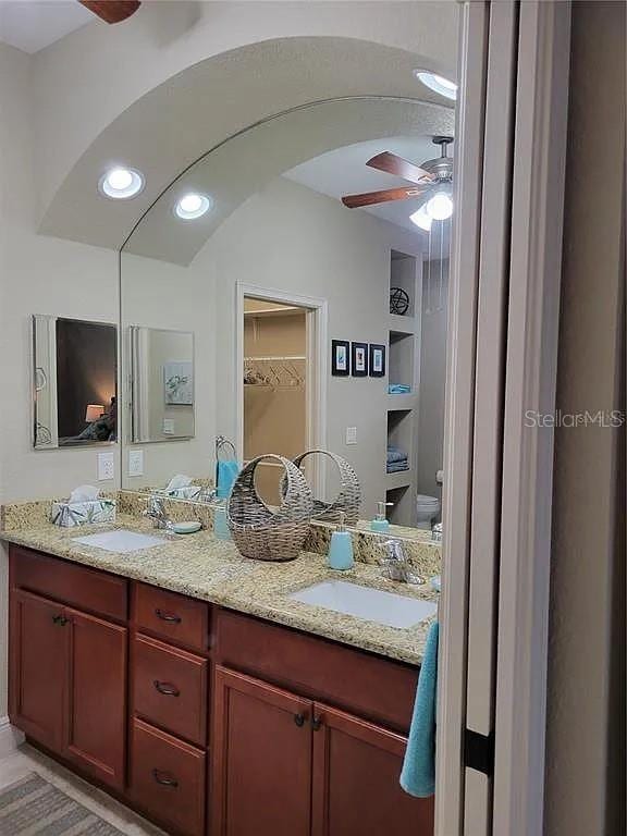 142 Yellow Pine Dr, Rotonda West, FL 33947 - bathroom featuring ceiling fan, double vanity, recessed lighting, toilet, and a spacious closet