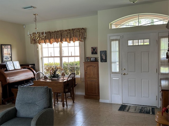 foyer featuring a chandelier, tile patterned floors, and baseboards