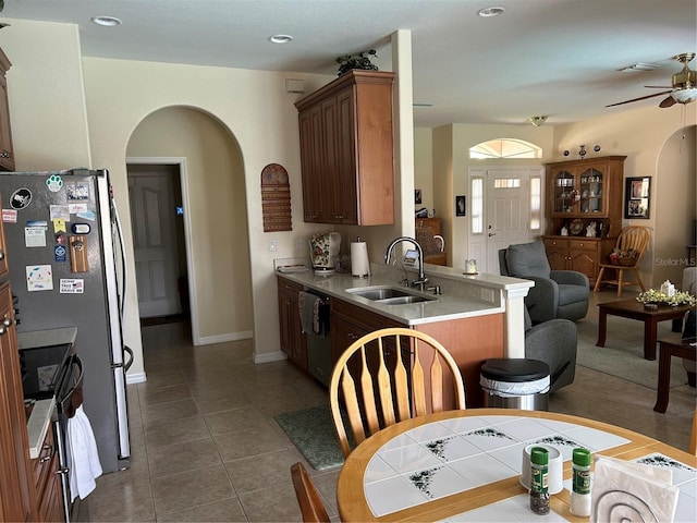 kitchen with a sink, arched walkways, appliances with stainless steel finishes, open floor plan, and ceiling fan