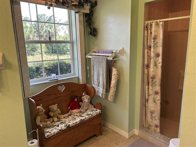 bathroom with a shower stall, tile patterned floors, and baseboards