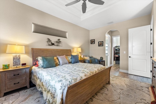 15044 San Domingo Blvd, Port Charlotte, FL 33981 - bedroom featuring a tray ceiling, arched walkways, light wood-style flooring, ceiling fan, and baseboards
