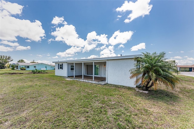 11 Oakland Hills Rd, Rotonda West, FL 33947 - back of property featuring stucco siding, a lawn, and a patio