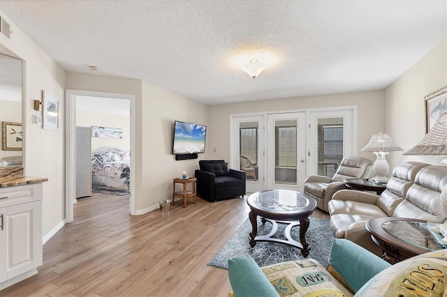 507 Pine Hollow Cir Unit 507, Englewood, FL 34223 - living room with light wood-type flooring, baseboards, a textured ceiling, and french doors