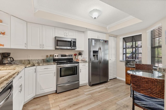 507 Pine Hollow Cir Unit 507, Englewood, FL 34223 - kitchen with stainless steel appliances, a raised ceiling, crown molding, light wood finished floors, and white cabinetry